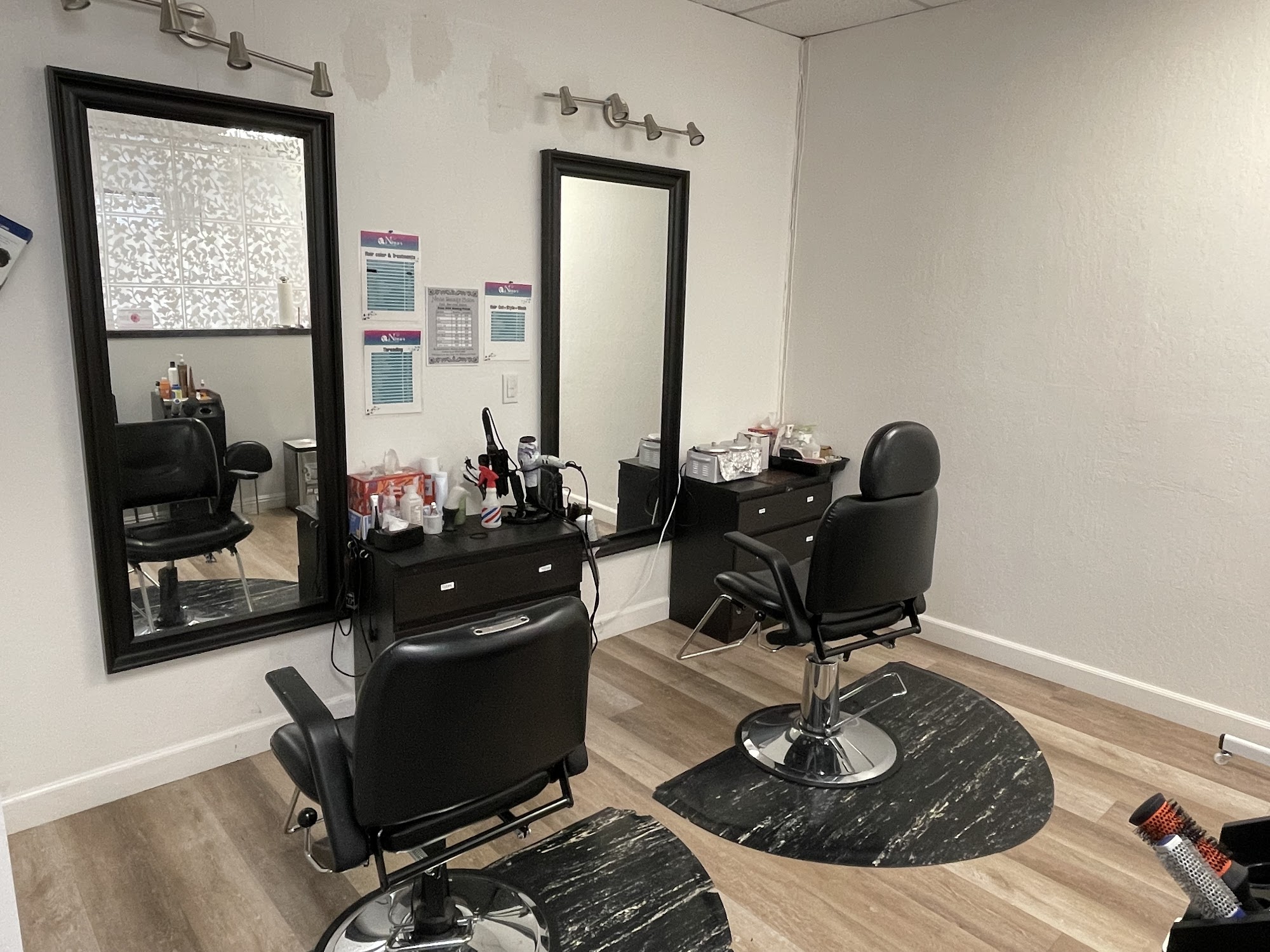 Two black-framed styling stations, wood floor, and Nina's Beauty Salon wall menus inside Suite 256.