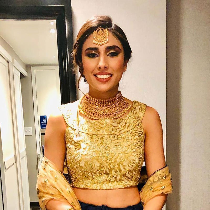 Bride in gold embroidered blouse with maang tikka, smoky gold eyes, and a voluminous updo.